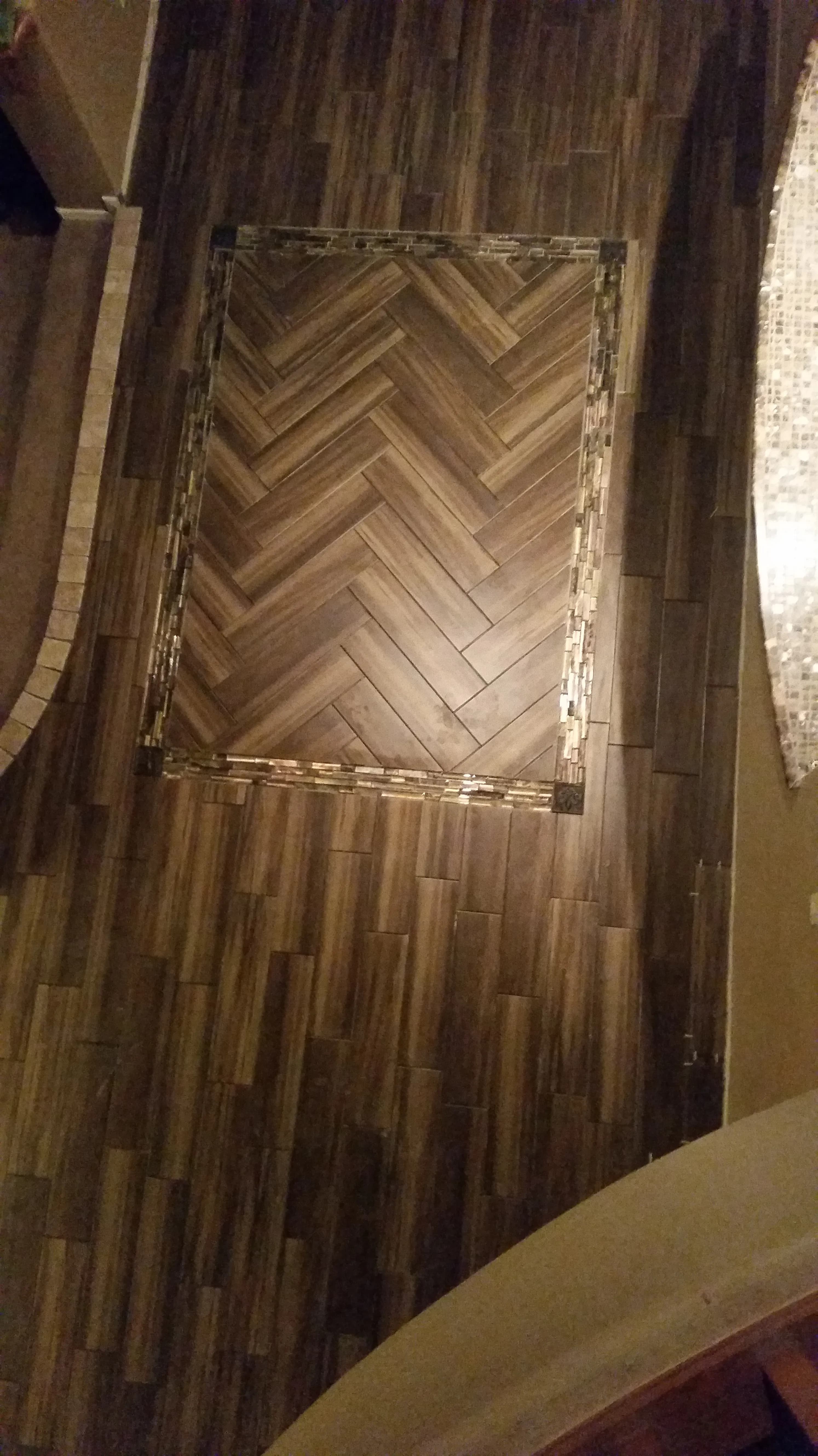 Dark wood-look tile floor with a herringbone inlay detail in a narrow hallway