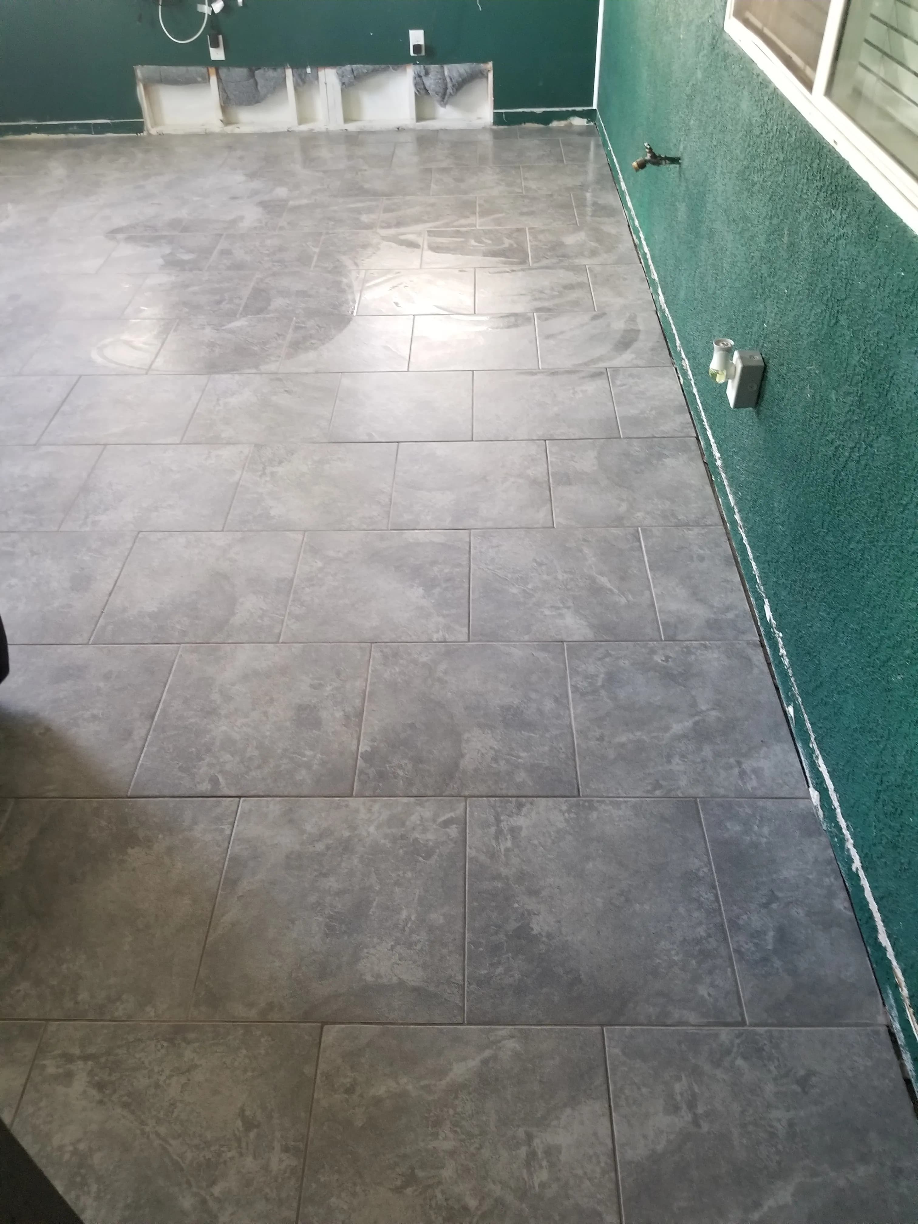 Large-format gray floor tiles installed in a room with dark grout lines
