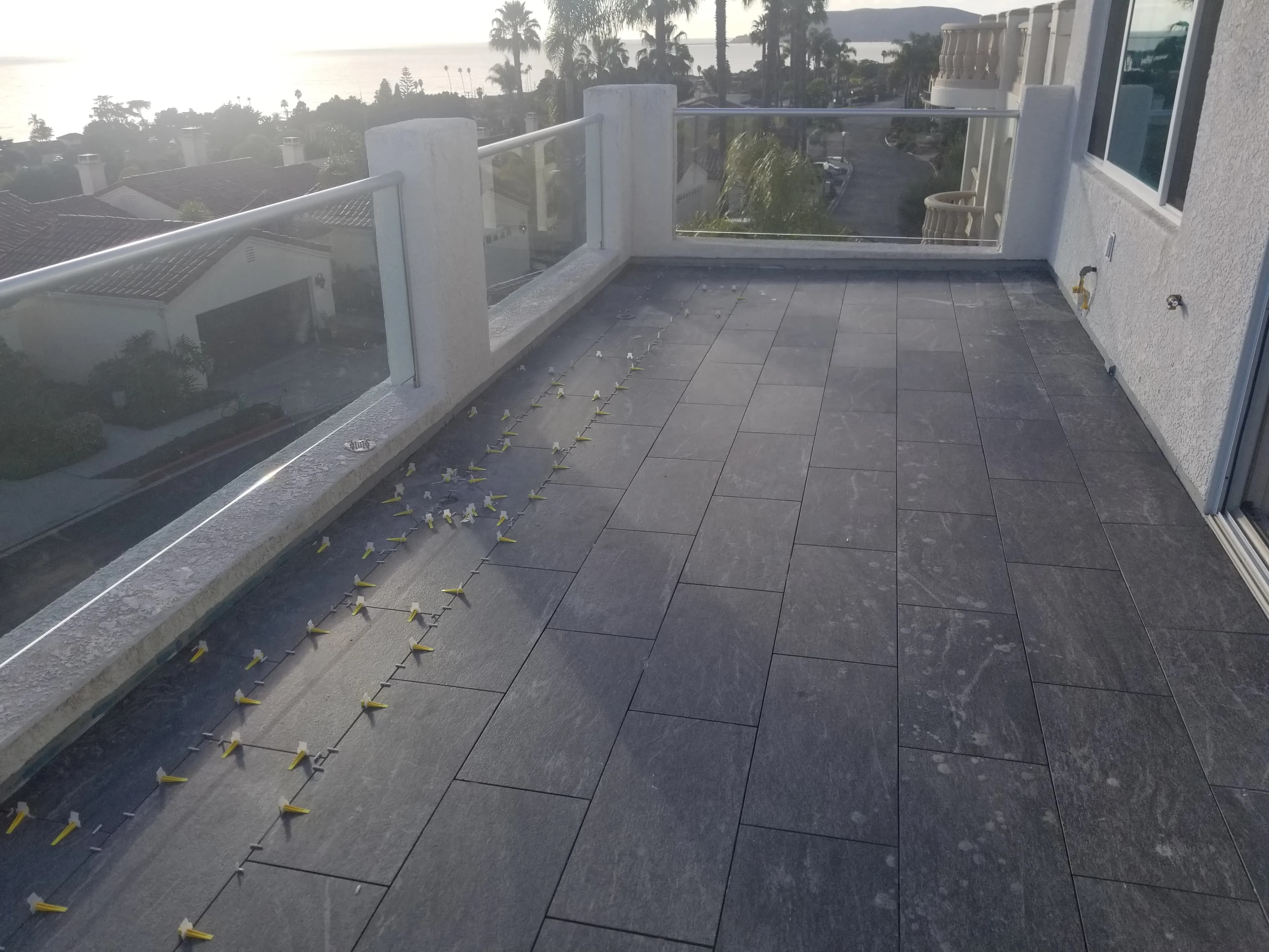 Outdoor balcony with large-format dark tile flooring and glass railing