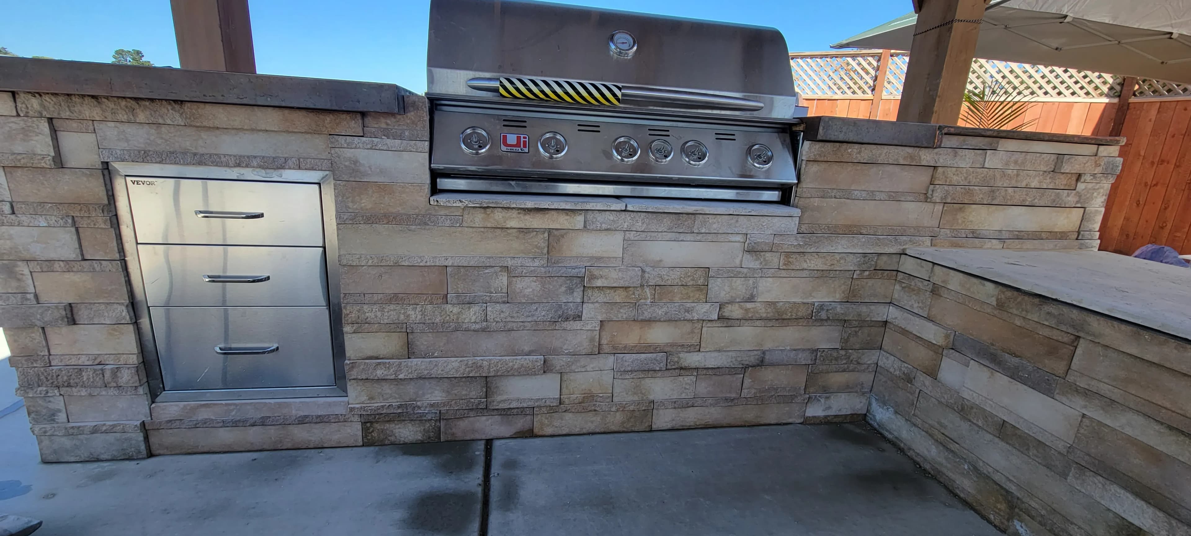 Outdoor kitchen area with stacked stone surround and built-in grill