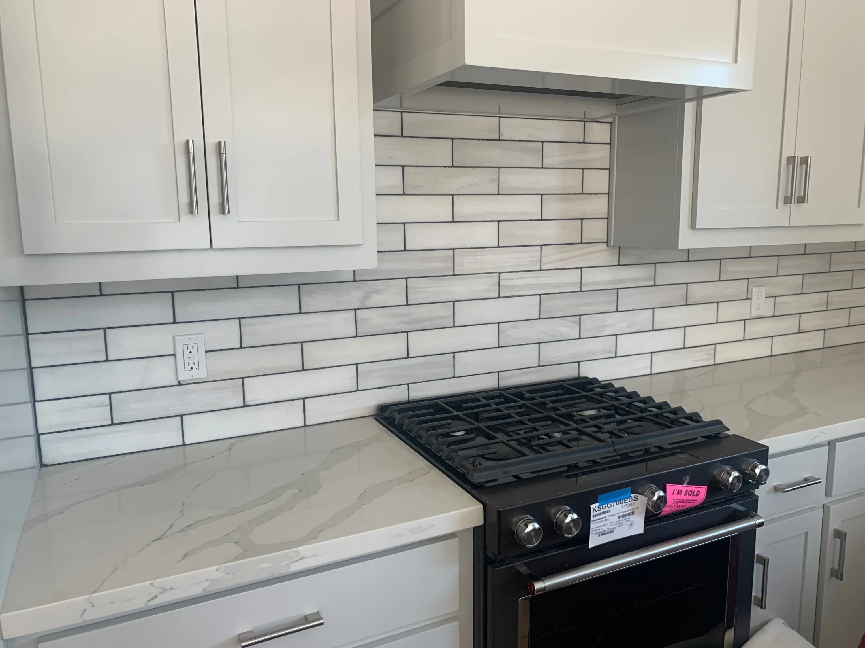 White subway tile backsplash installed behind a kitchen range and countertop