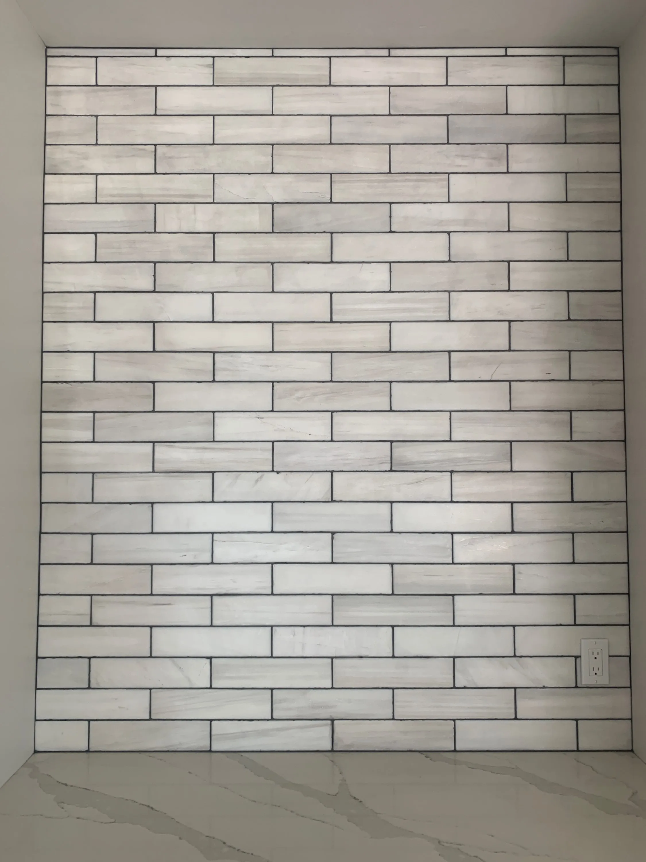 White subway tiles installed vertically as a full-height backsplash wall