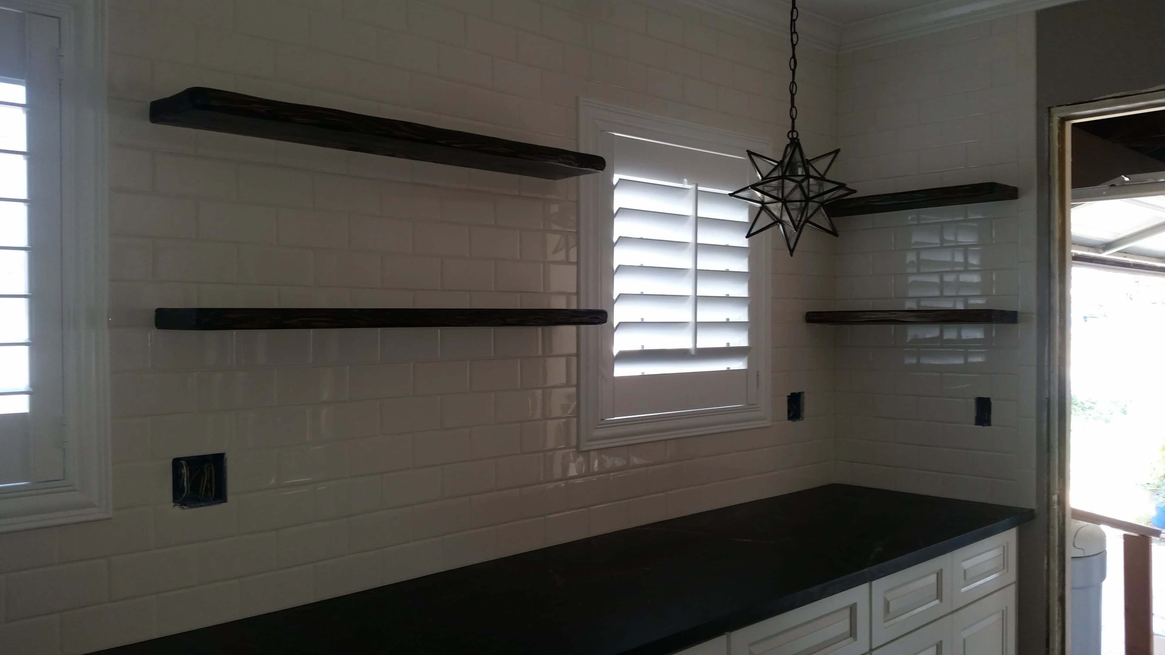 Tile backsplash installed behind floating kitchen shelves and countertop