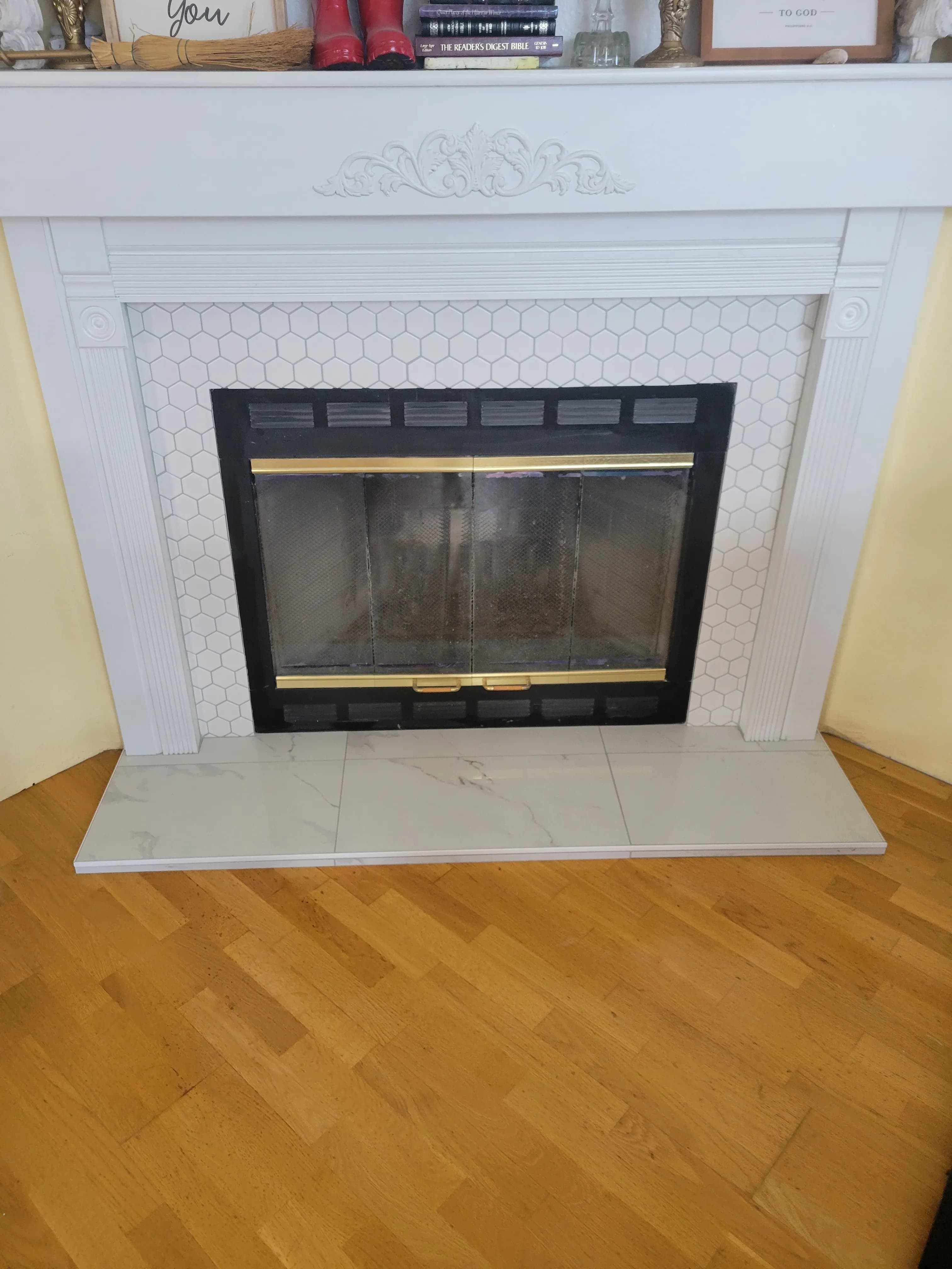 Fireplace with white tile surround, decorative mantel, and tiled hearth